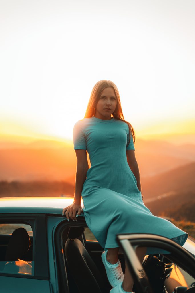 Fotoshooting eines Models im Kleid, sitzt auf dem Auto, Hintergrund Sonnenuntergang. Fotoshooting in Karlsruhe und Umgebung