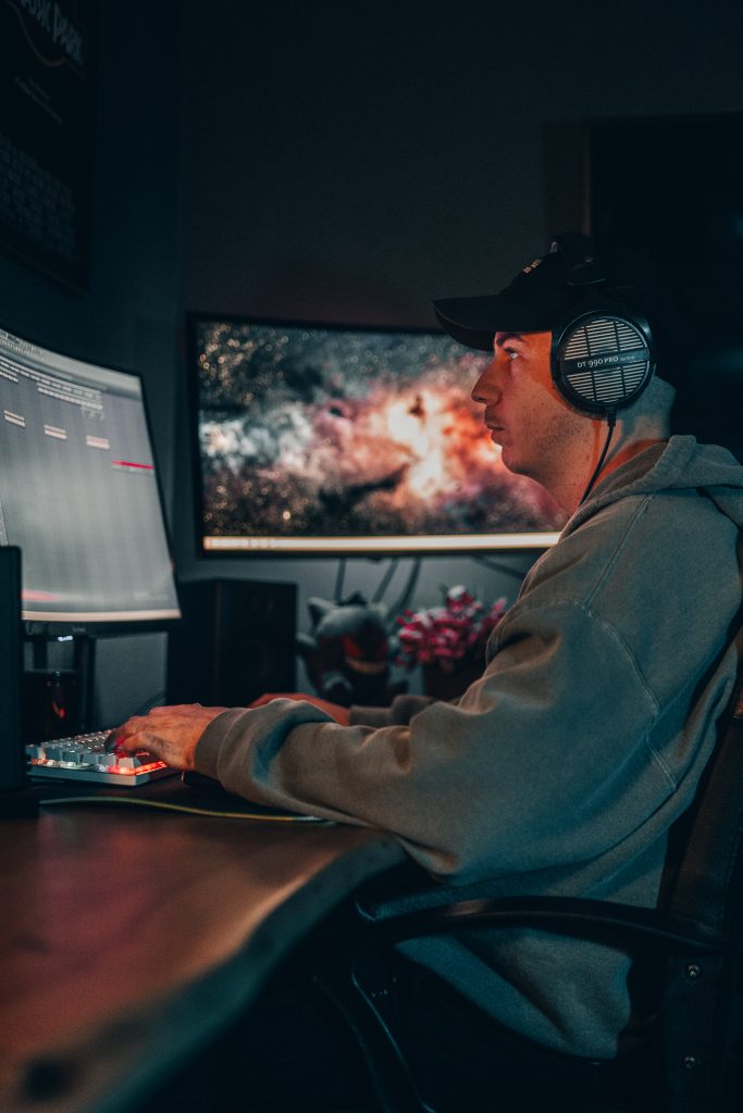 Beat Producer am PC arbeitet mit FL Studio, moody fotoshooting zu Hause mit Headset auf dem Kopf